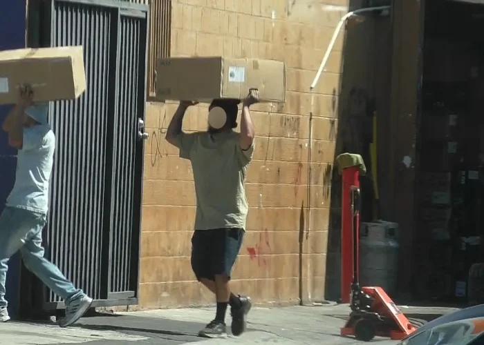 Surveillance image of a parent carrying boxes at an automotive shop during a child custody and support investigation.