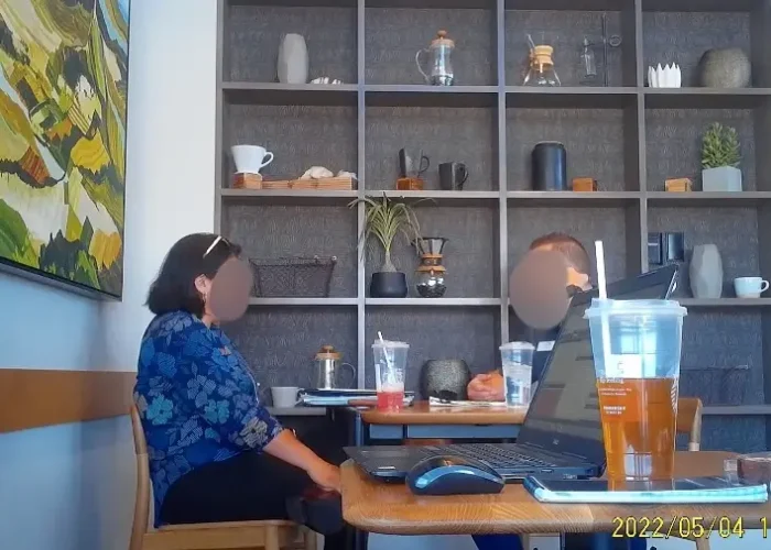 crystal clear covert video Surveillance photograph of two people seated at a cafe table.