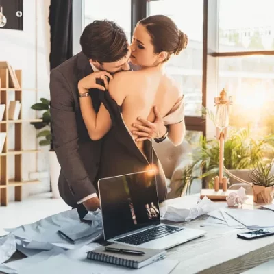 man and woman kissing in office
